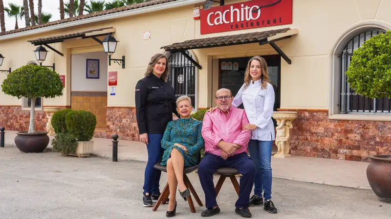 La familia Cachito a la puerta del restaurante, con Noelia y Lidia de pie