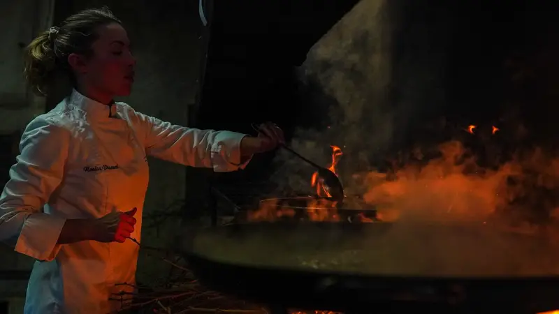 Noelia Pascual junto al fuego de sarmiento, entre el humo de la cocina