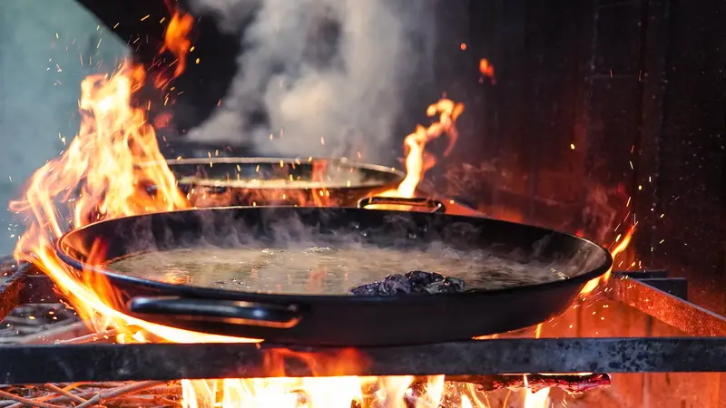 Paella al fuego de sarmiento, con las llamas lamiendo los bordes