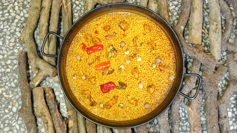 Arroz con conejo y serranas, visto desde arriba, sobre un lecho de sarmientos