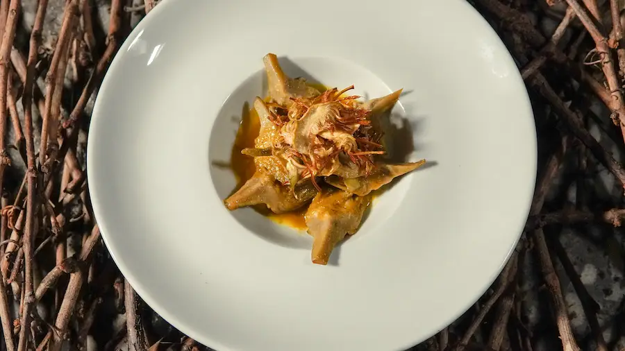 Flor de alcachofa de la huerta en plato blanco sobre sarmientos