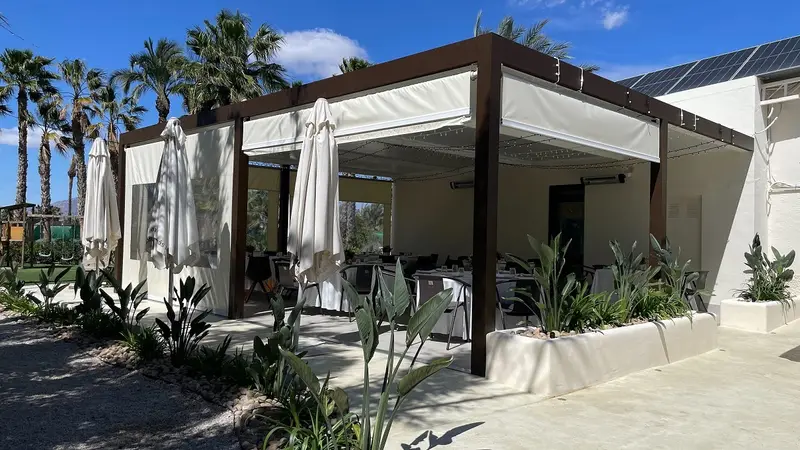 Terraza del restaurante entre palmeras y jardín